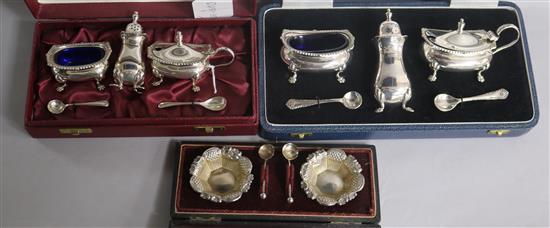 Two cased modern silver three piece condiment sets and a cased pair of Victorian silver salts and spoons.